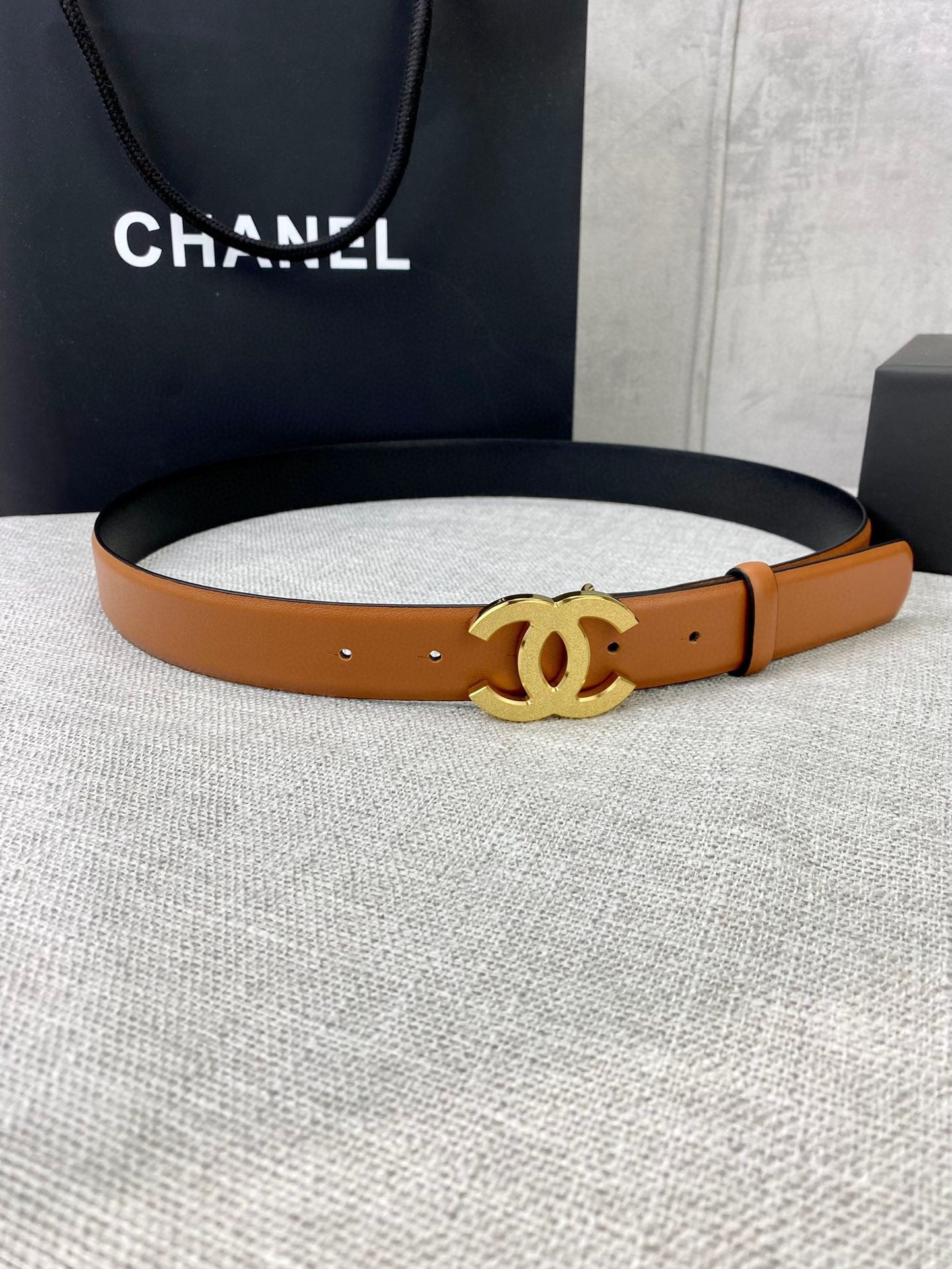 Tan leather belt with gold-tone CC buckle and punched holes.