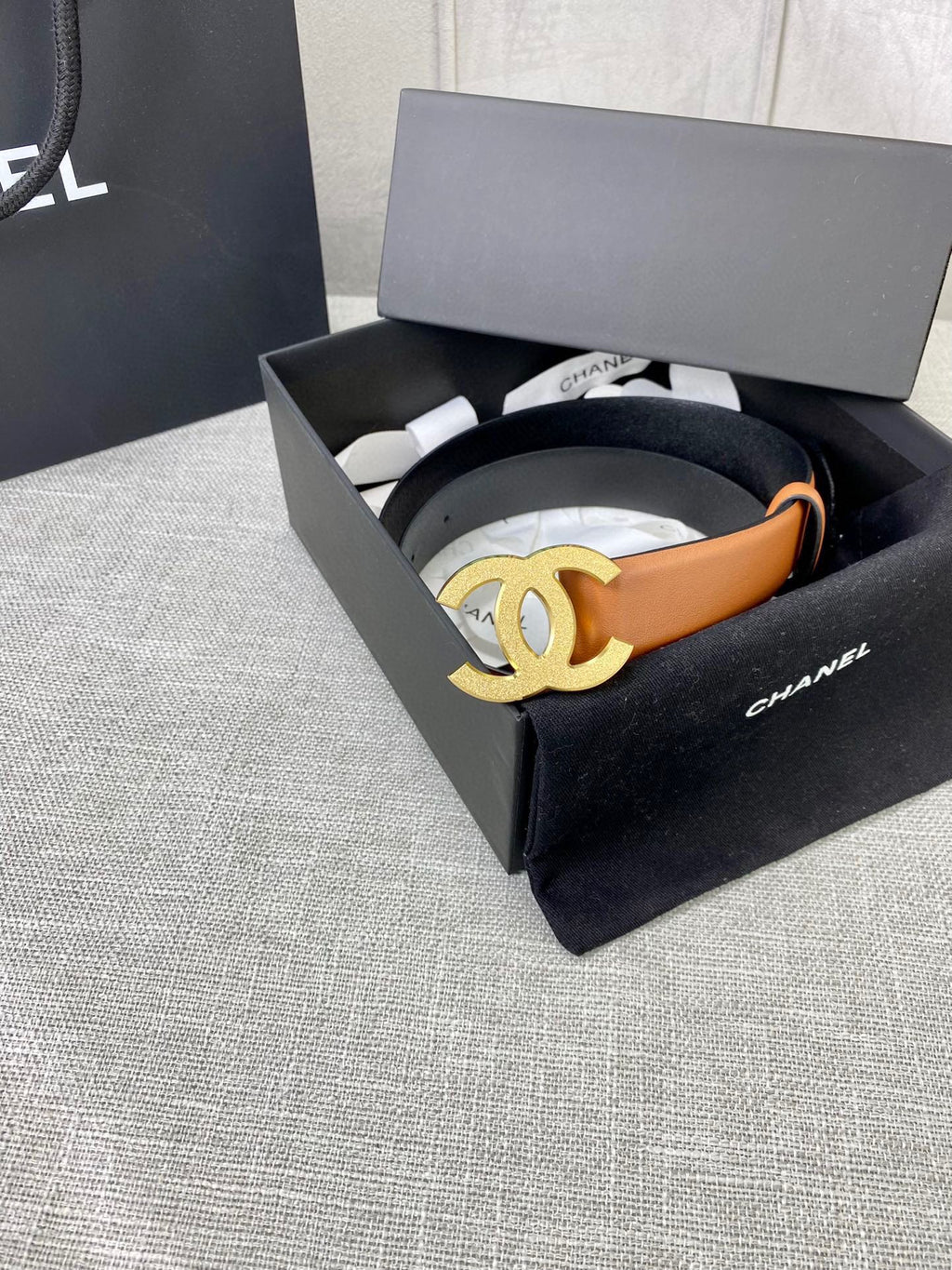Tan leather belt with gold-tone CC buckle, in a black gift box.
