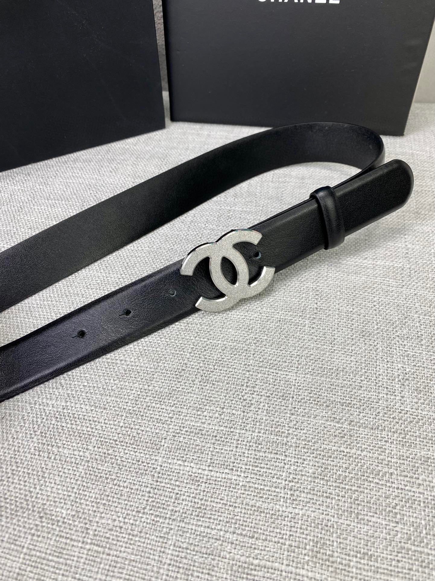 Chanel belt with black leather strap and silver-tone CC buckle, side view