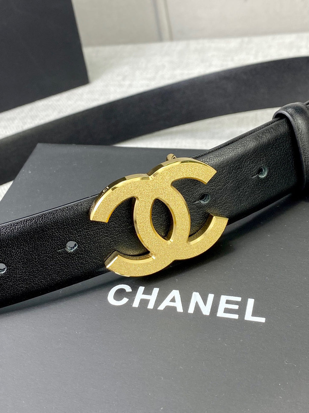 Chanel belt with black leather strap and gold-tone CC logo buckle, angled view