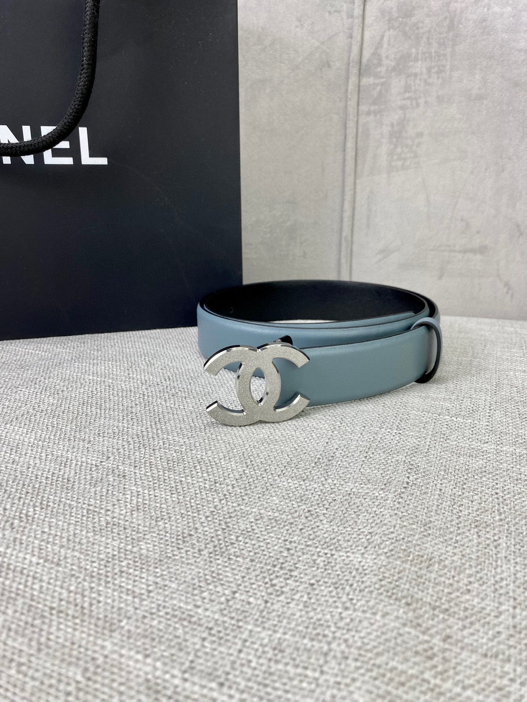Chanel belt with light blue leather strap and metallic logo buckle, laid flat.