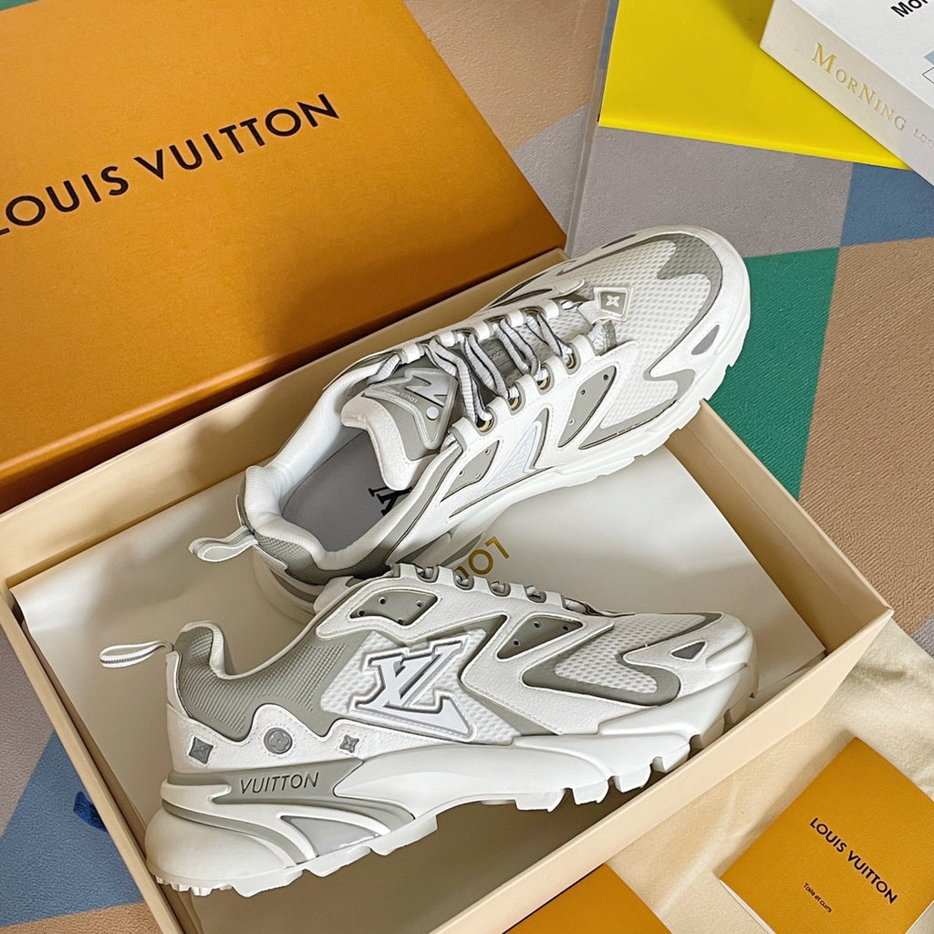 White and gray lace-up sneakers in an open box, with signature-style logo overlays