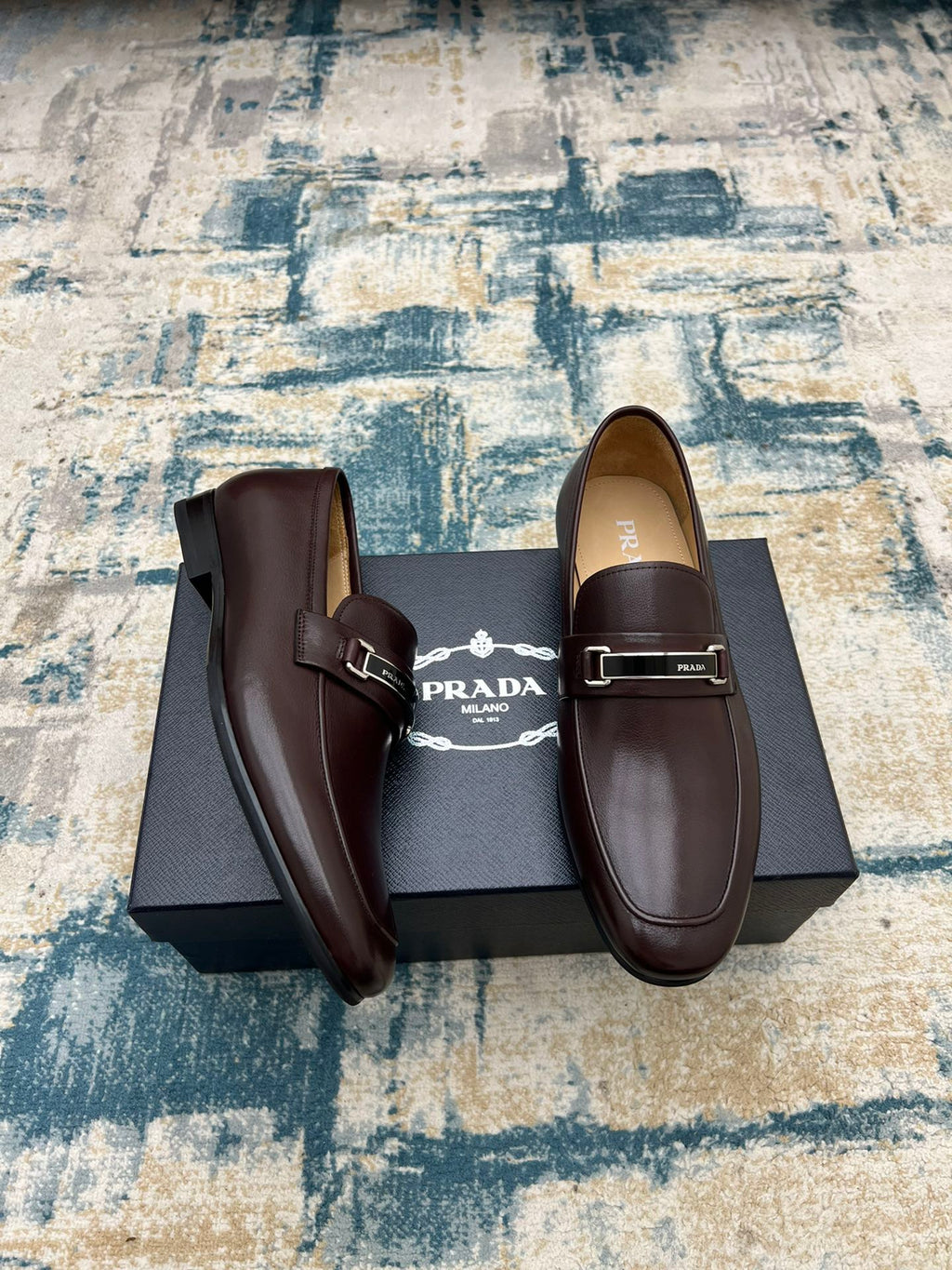 Prada unisex leather loafers with metal buckle strap, dark brown, one shoe turned