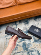 Prada unisex leather loafer with metal buckle strap, dark brown, held up side view