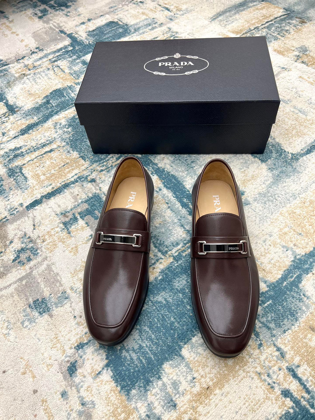 Prada unisex leather loafers with metal buckle strap, dark brown, front view pair