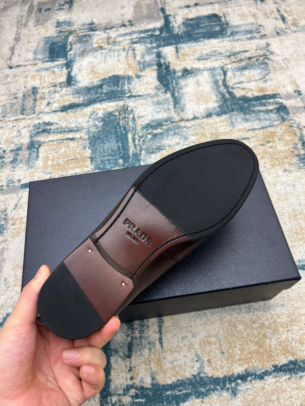 Prada unisex loafer outsole view, dark brown leather with logo stamp