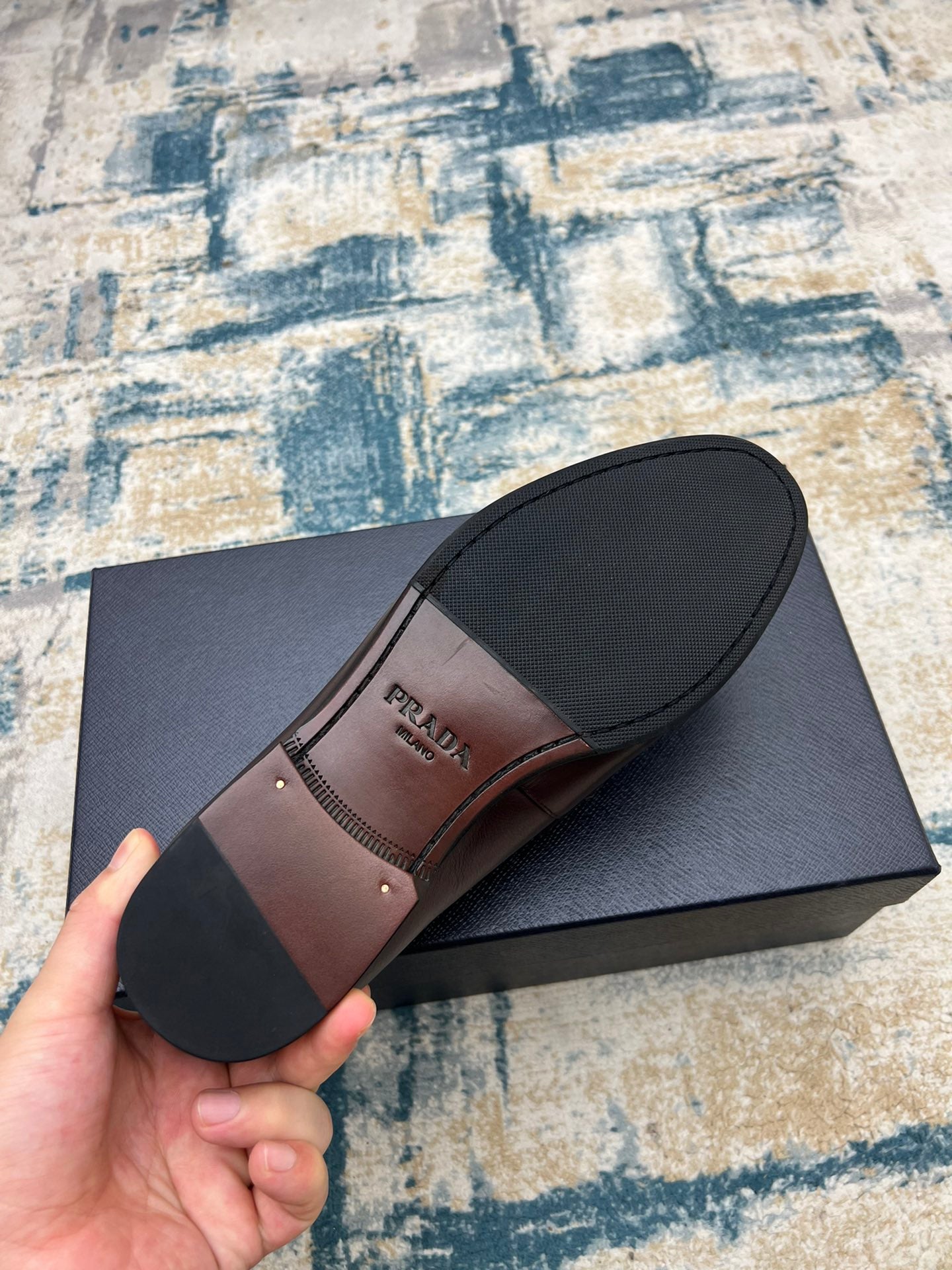 Prada unisex loafer outsole view, dark brown leather with logo stamp