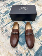 Pair of brown Prada leather loafers with silver buckle strap, shown with gift box