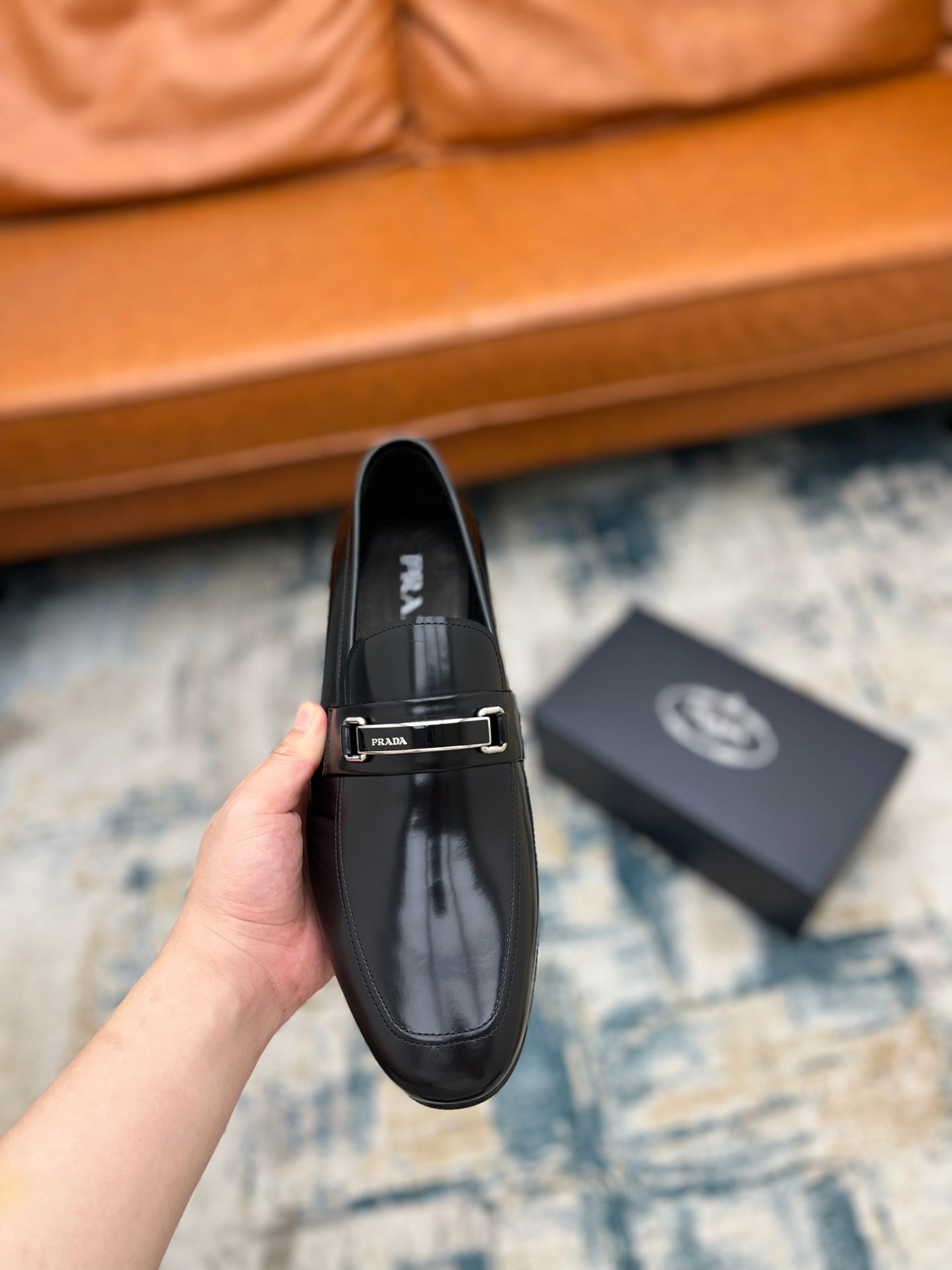 Prada unisex black loafer with buckle strap, front close-up held