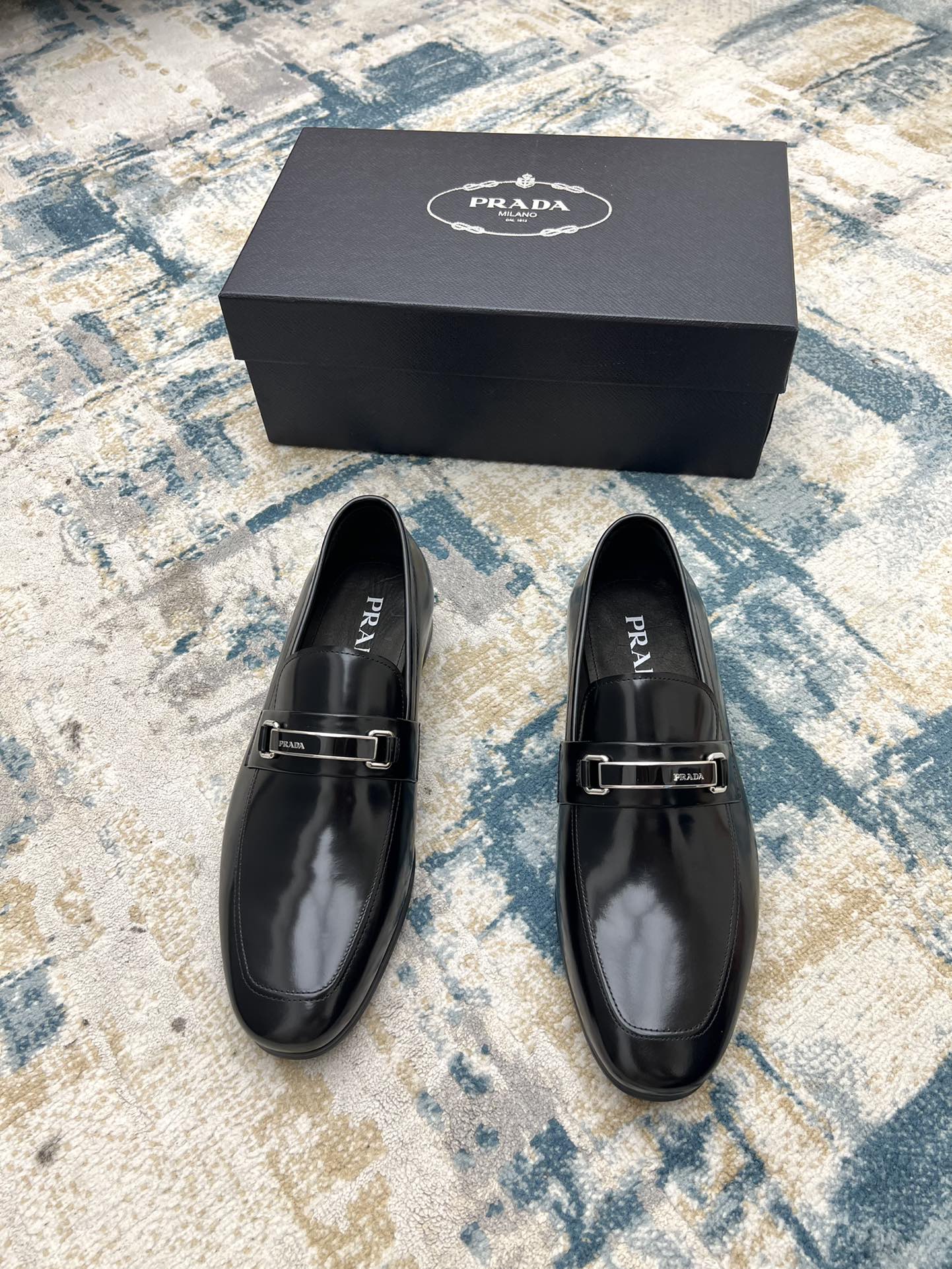 Prada black leather loafers with buckle strap, shown with matching shoe box