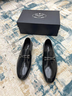 Prada unisex polished black loafers with buckle strap, top view on box