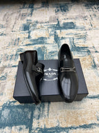 Pair of Prada black leather loafers with buckle strap and glossy upper