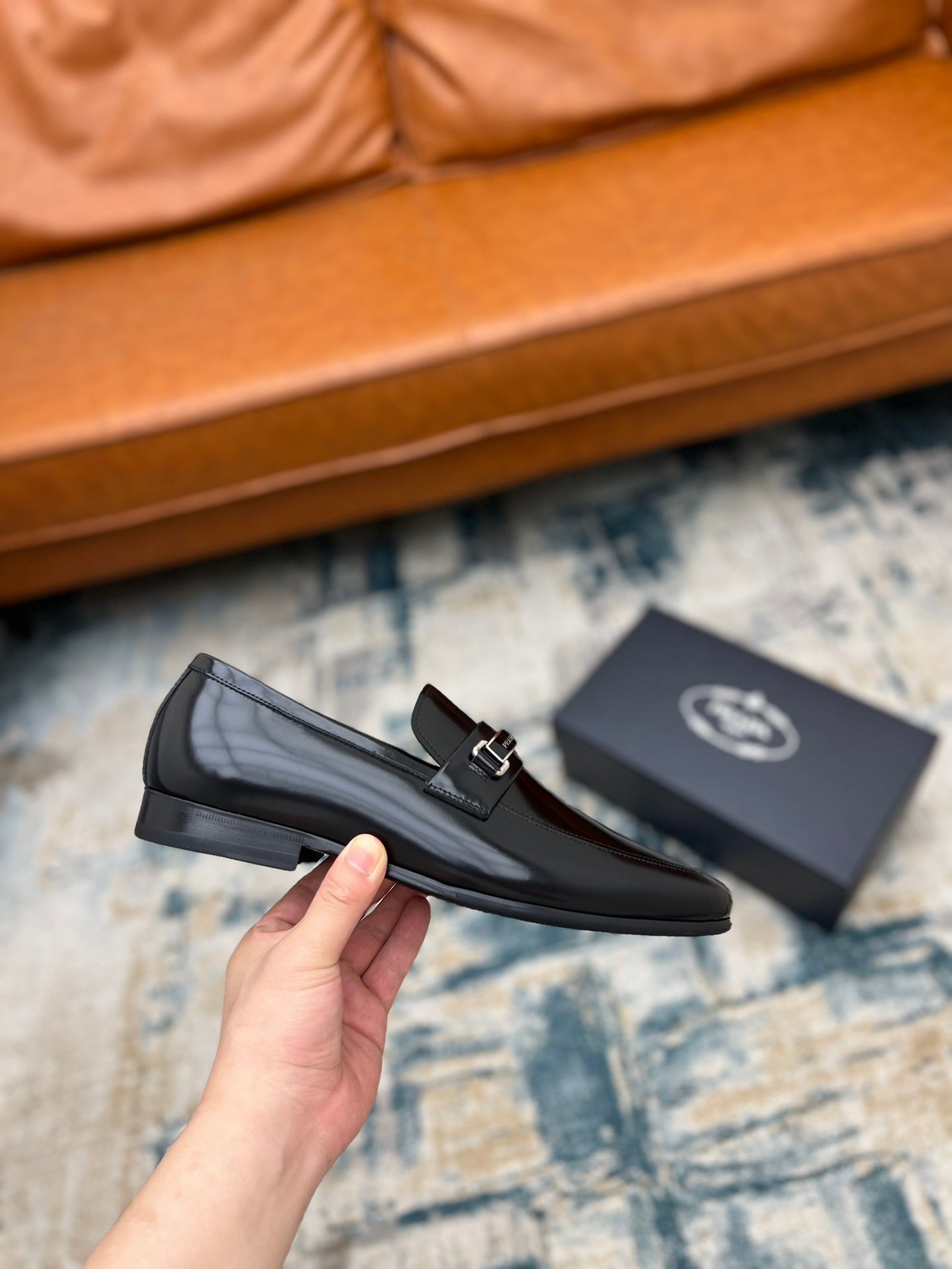 Prada black leather loafer with buckle strap, hand-held side view