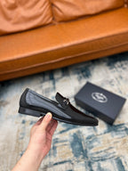 Prada unisex black loafer with buckle strap, held in hand side view