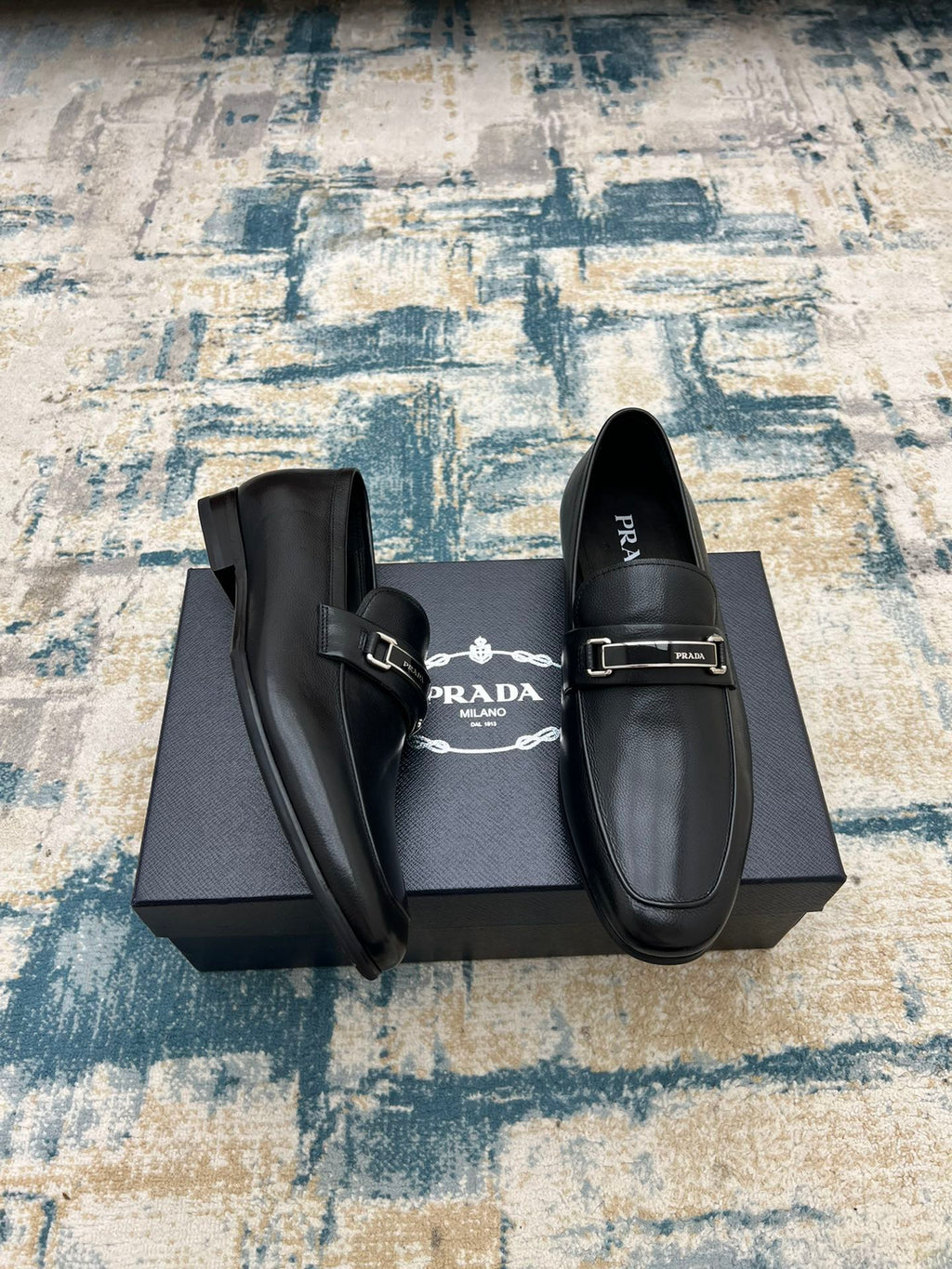 Prada unisex loafers with buckle strap and lining, black slip-on style.