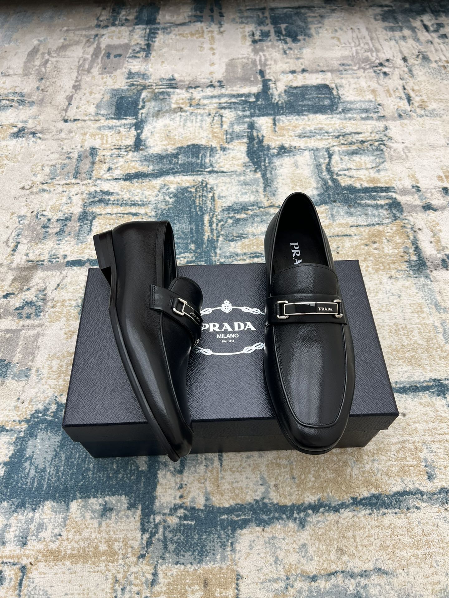 Prada unisex loafers with buckle strap and lining, black slip-on style.