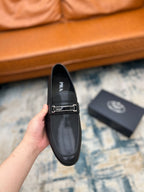 Prada unisex loafers, black with silver buckle strap, front view in hand.