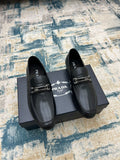 Prada unisex leather loafers, black with silver buckle strap, slip-on design.