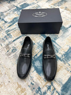 Prada unisex leather loafers, black with silver buckle strap, front view of pair.