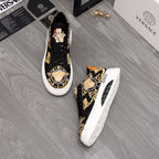 Pair of black low-top sneakers with gold baroque print and colorful heel detail, white soles.