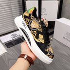Black sneakers with gold baroque print and rainbow heel panel, lace-up front.