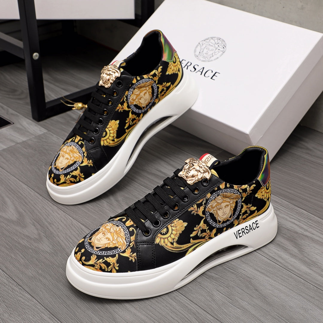 Black low-top sneakers with gold baroque print, lace-up front, Medusa-style emblem.