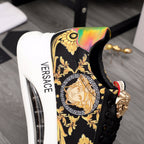 Black sneakers with gold baroque print and rainbow heel panel, gold-toned lace hardware.