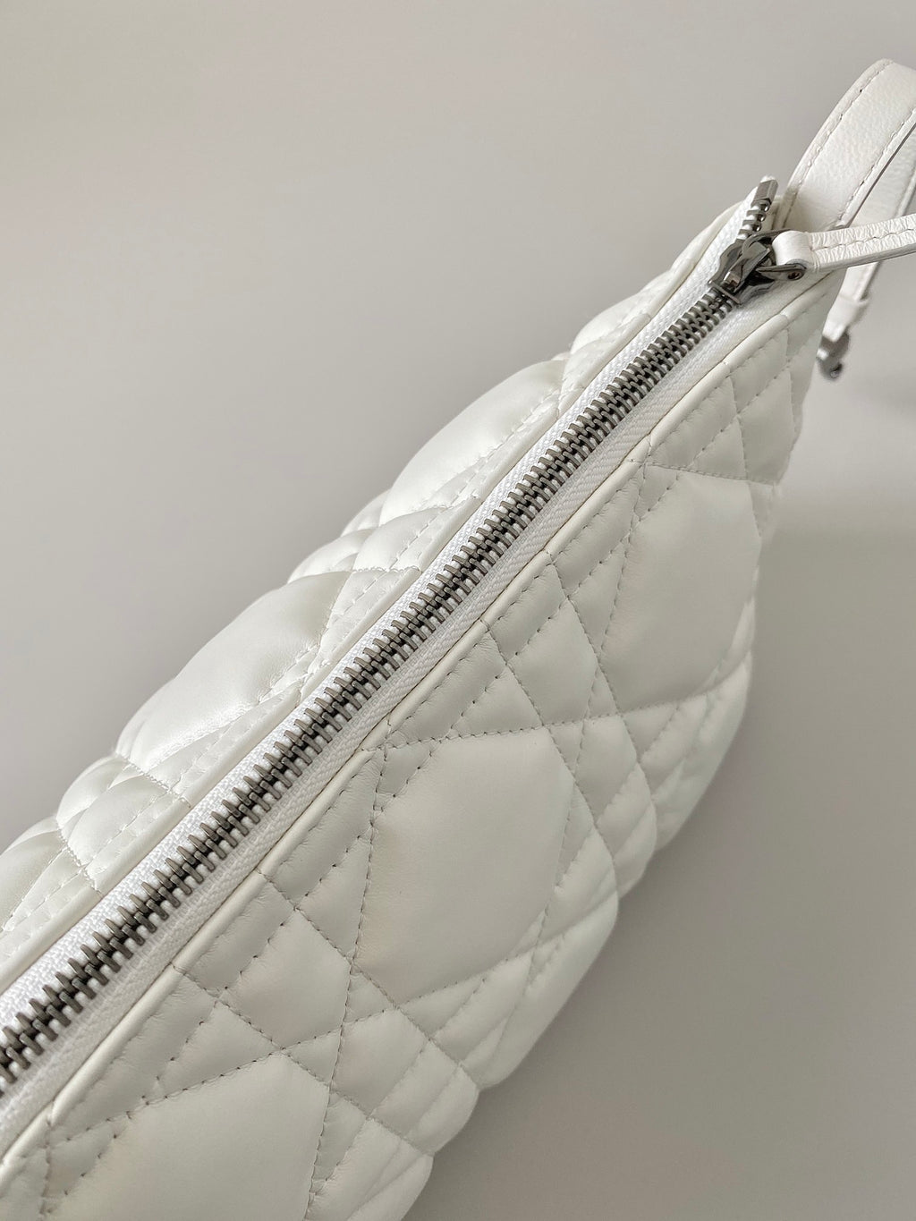 White quilted Dior bag with long top zipper and diagonal panel seams