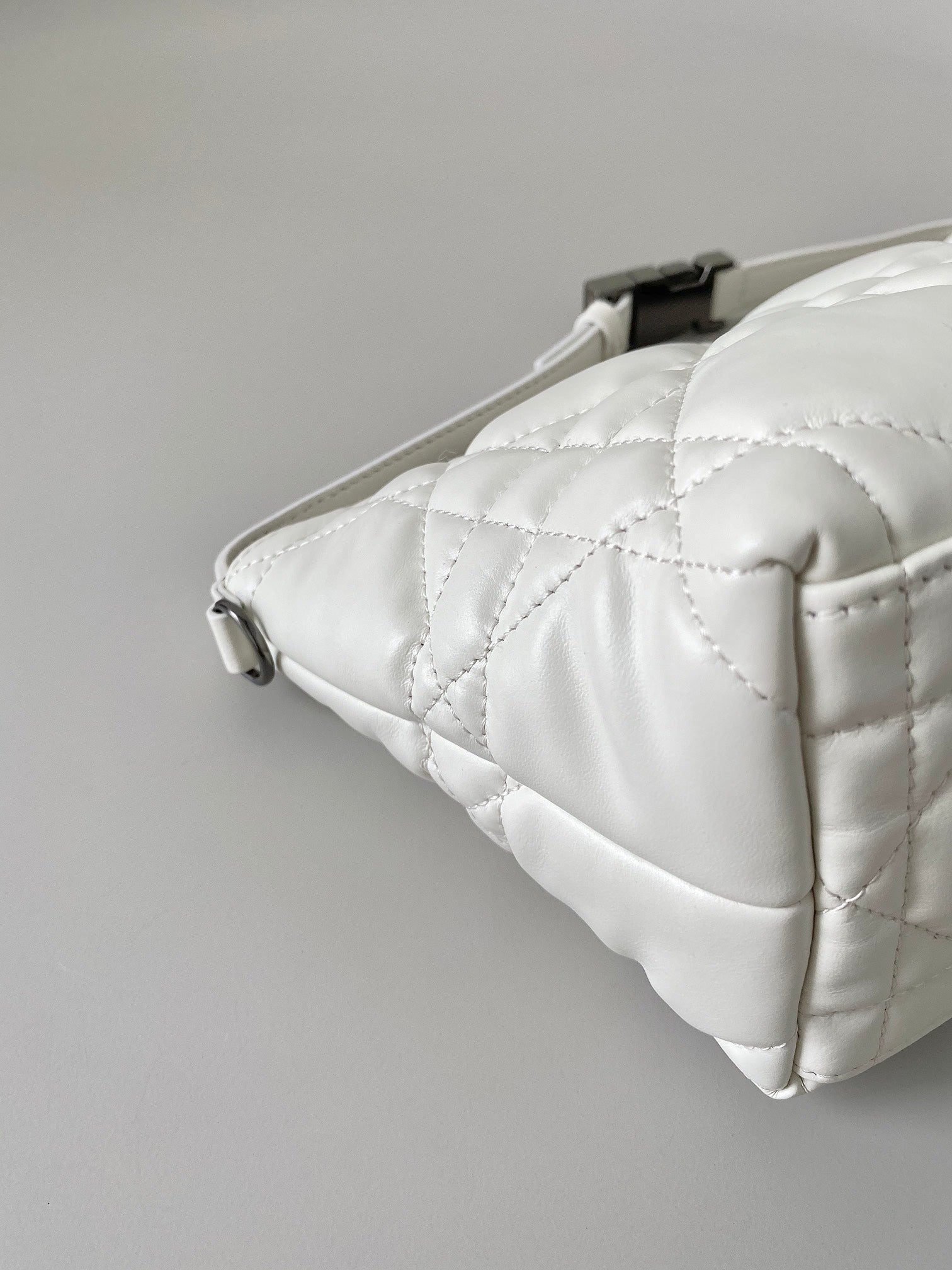 Quilted white Dior bag corner detail with top zipper and stitched panels
