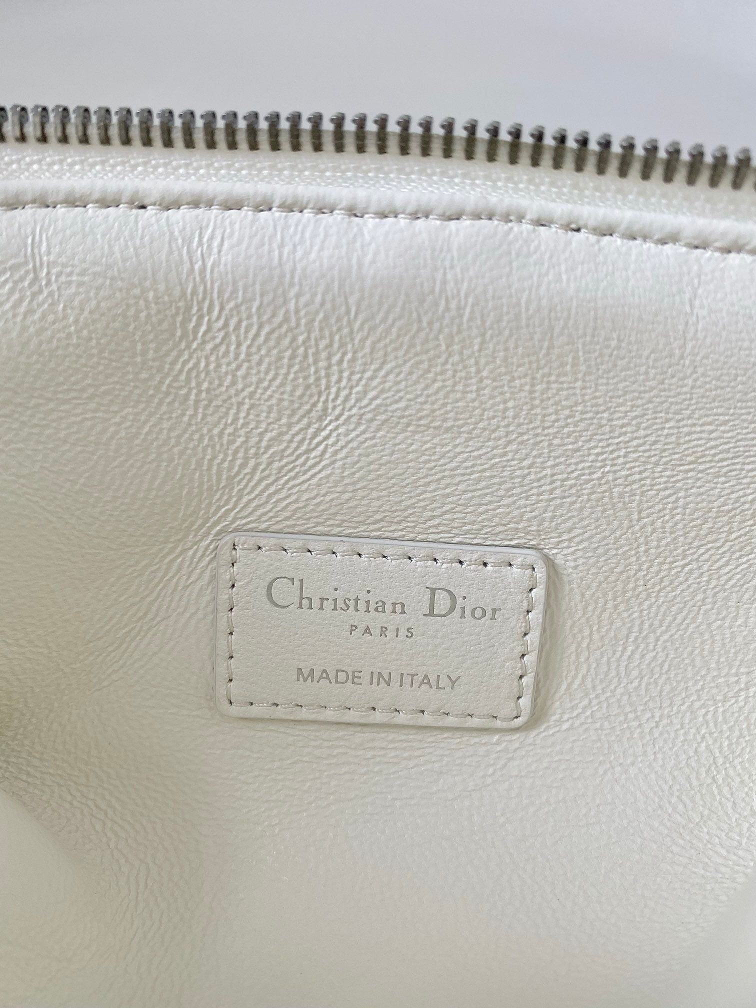 White leather bag tag reading Christian Dior, Paris, made in Italy.