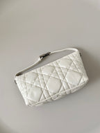 White quilted wristlet bag with top zip and adjustable strap hardware.
