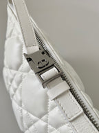 Top zip detail on white quilted Dior bag with metal zipper pull