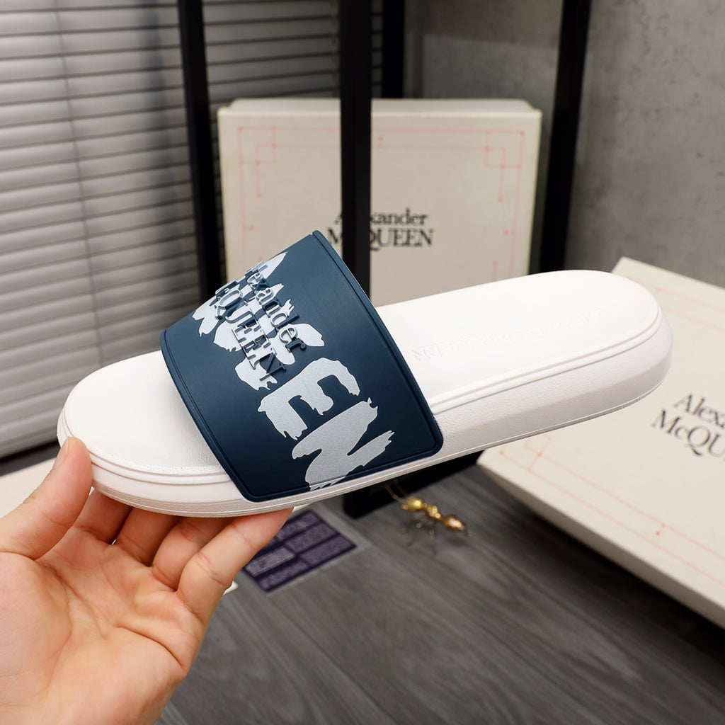 White slide sandal with navy strap and white logo graphic, angled view