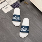 Pair of white slide sandals with navy logo strap and cushioned footbed