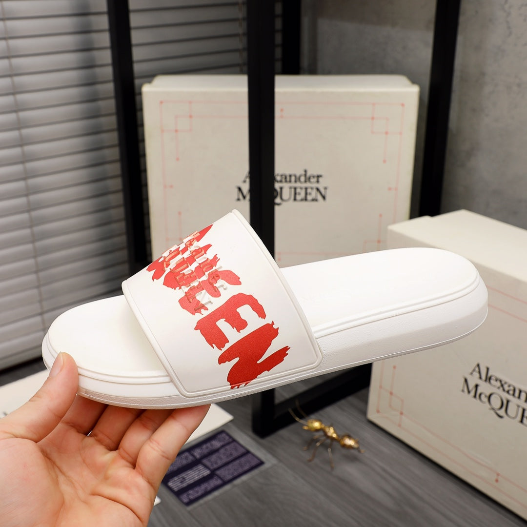 White slide sandal with red logo on wide strap in a hand