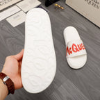 White slide sandal outsole with textured tread, plus red logo strap