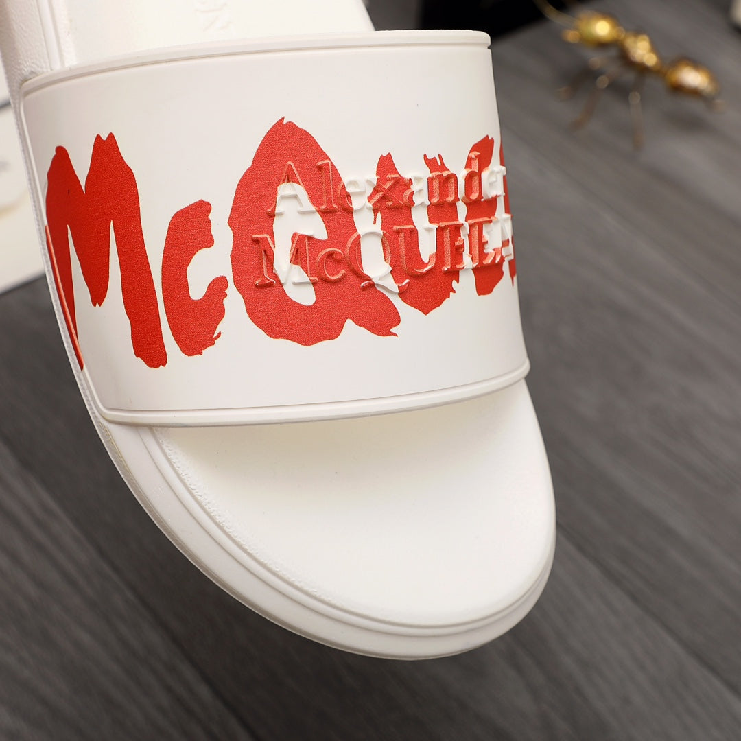 White slide sandal close-up with red McQueen logo on strap