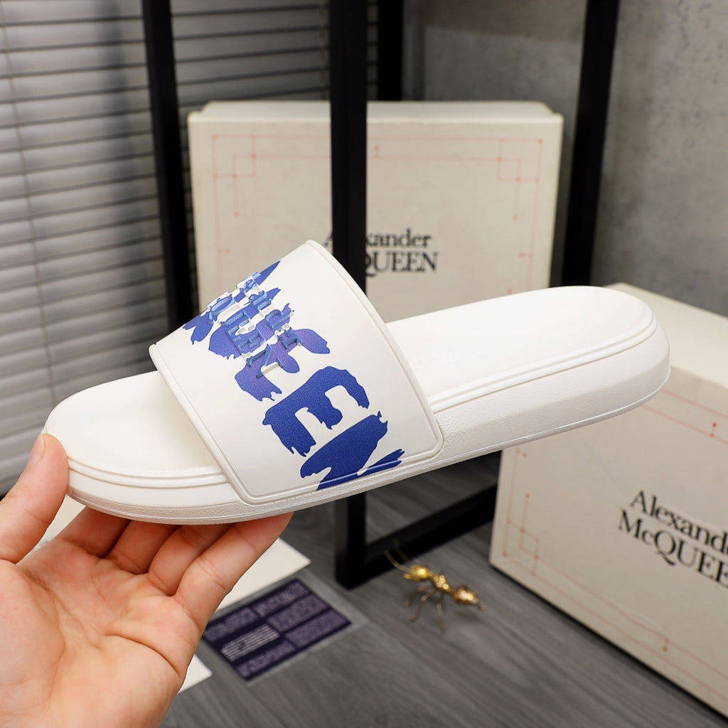 Alexander McQueen white slide sandals with blue logo strap, angled view