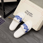 Alexander McQueen white slide sandals on box, blue logo straps visible
