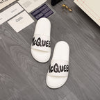 Pair of white slide sandals with black McQUEEN text on straps