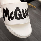 White slide sandal with oversized black McQUEEN graphic on strap