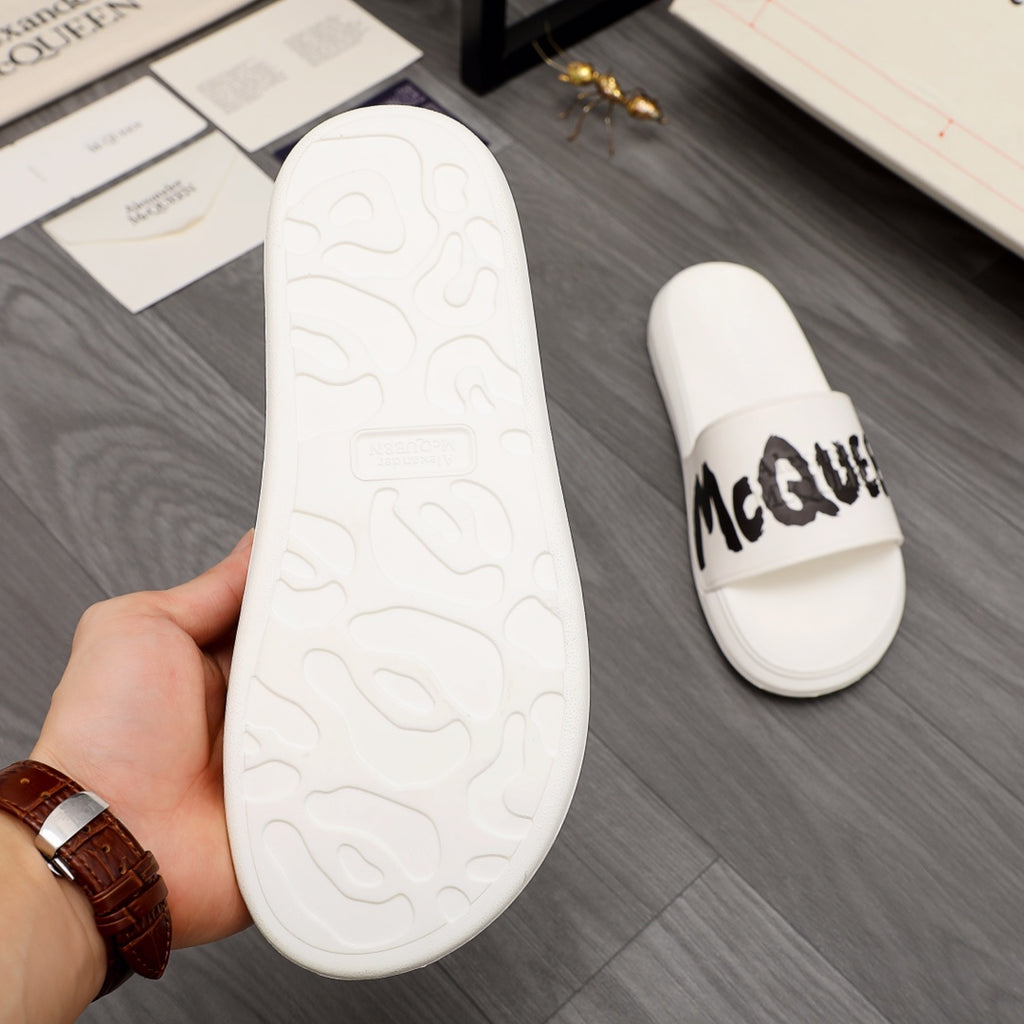 White slide sandals with textured outsole tread and McQUEEN logo on strap