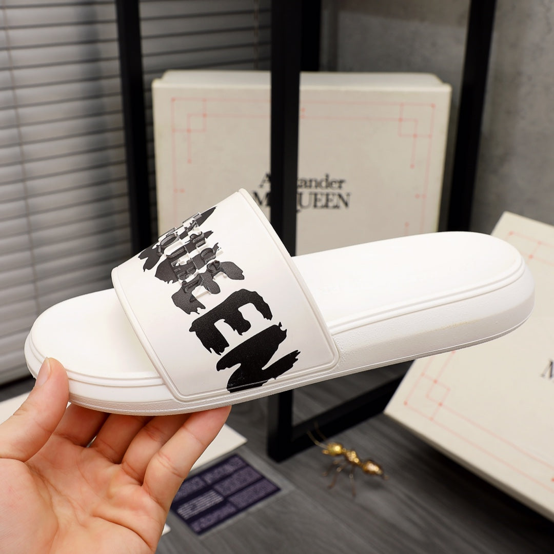 White slide sandals with black McQUEEN logo on the front strap