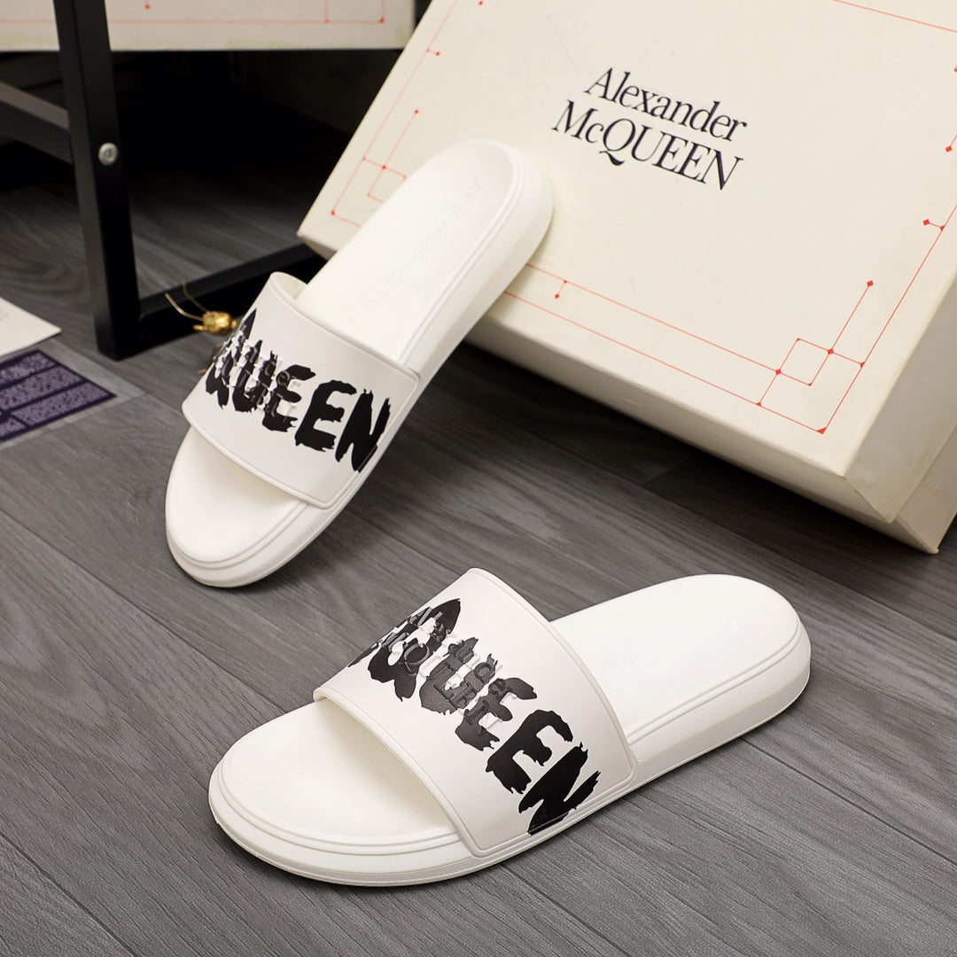 White slide sandals with black McQUEEN graphic across the strap