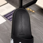 Black slide sandal footbed with textured leather look and raised logo detail.