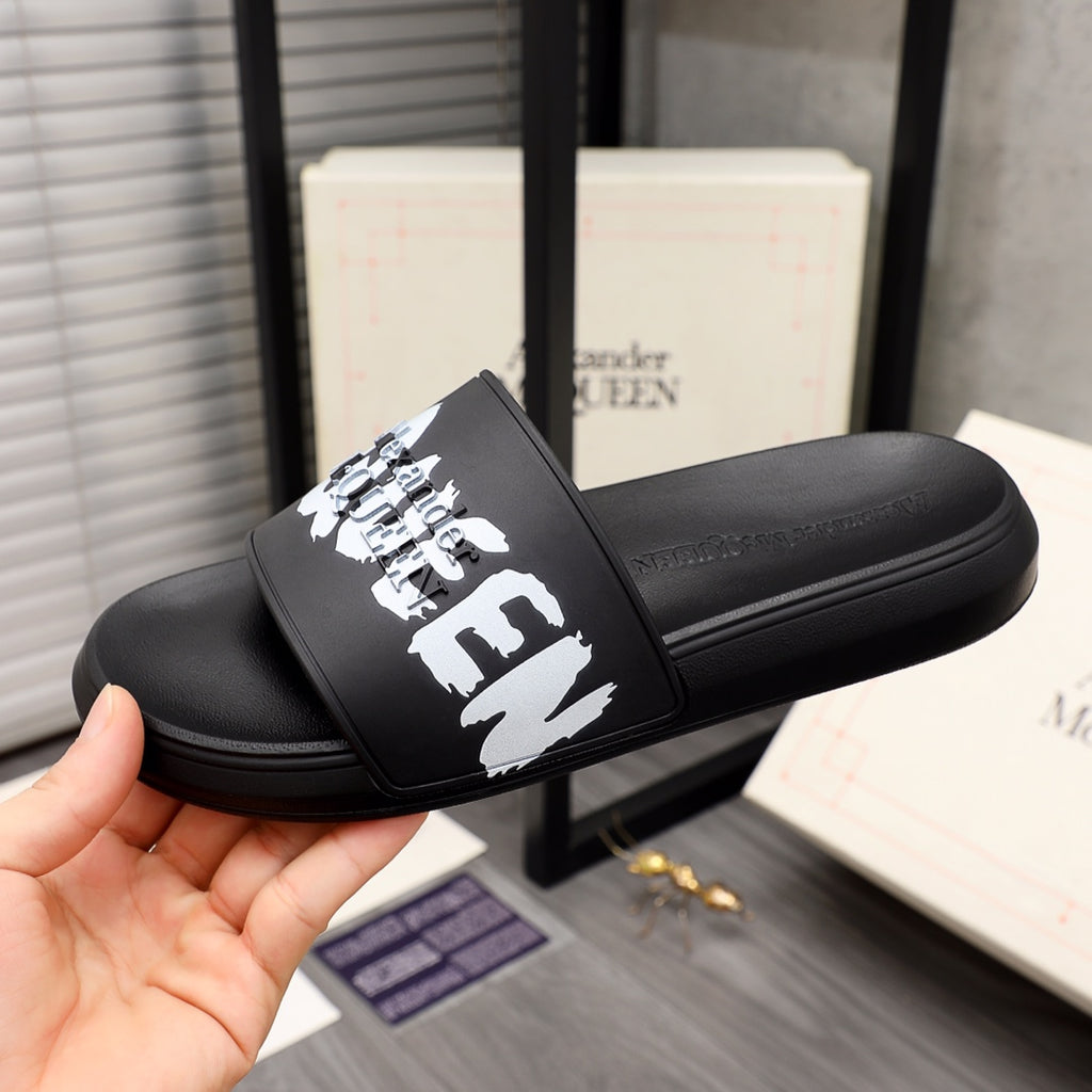 Black slide sandal with white McQueen graphic strap, shown from side angle.
