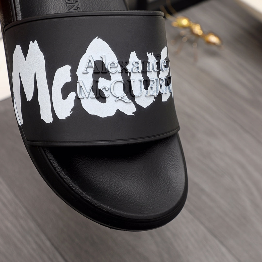 Close-up of black slide sandal strap with white McQueen graphic, Alexander McQueen.
