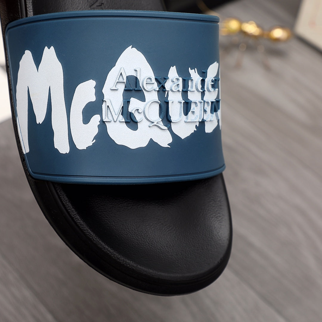 Black slide sandal with blue strap and oversized white logo lettering