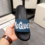 Black slide sandal with blue logo band, shown from side