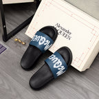 Black slide sandals with blue logo band and white lettering, angled view